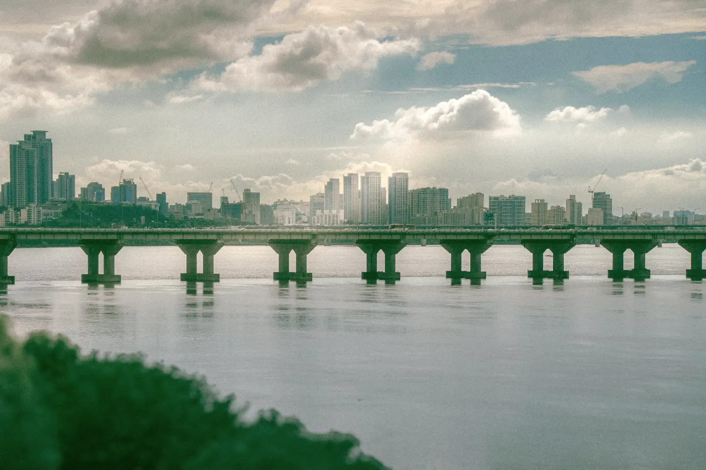 Seoul's skyline across the Han River, with a long road bridge in the foreground.